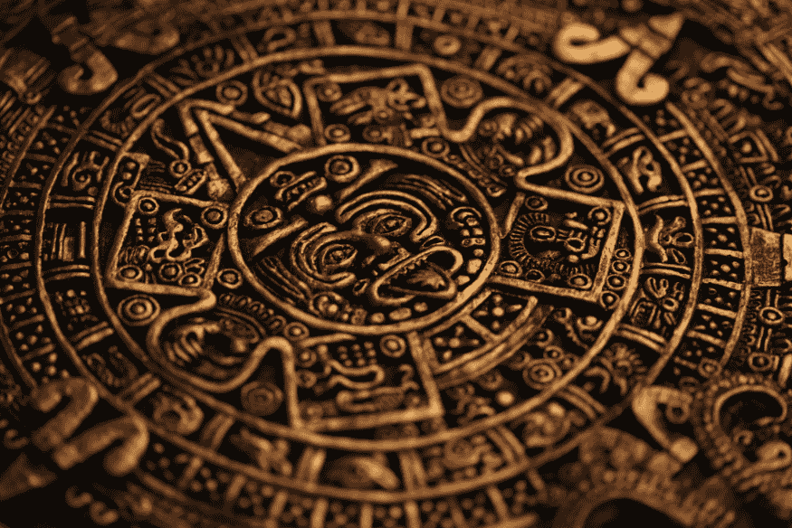 Calendário maia em pedra com símbolos circulares e entalhes detalhados, representando a astronomia nas civilizações maia e egípcia e sua relação com o tempo.