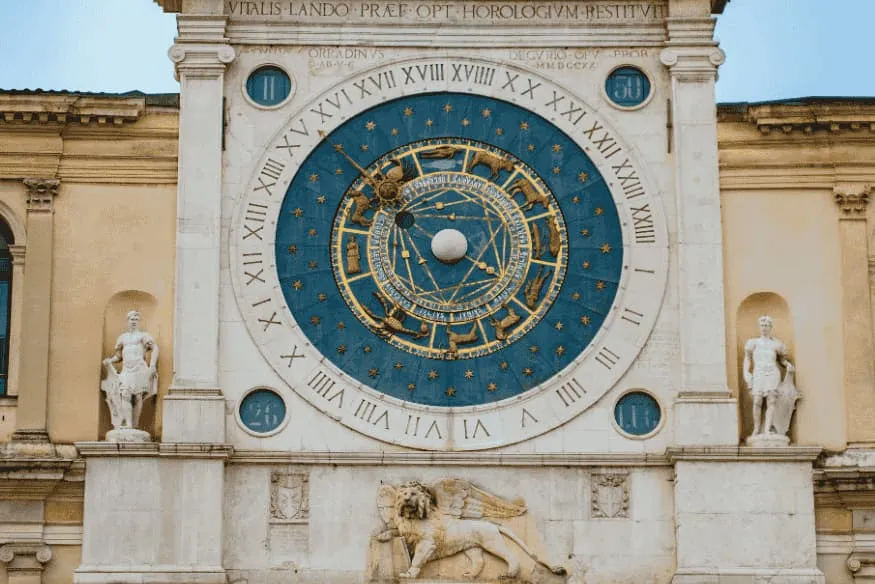 Relógio astronômico monumental em edifício histórico com mostrador azul e referências aos corpos celestes