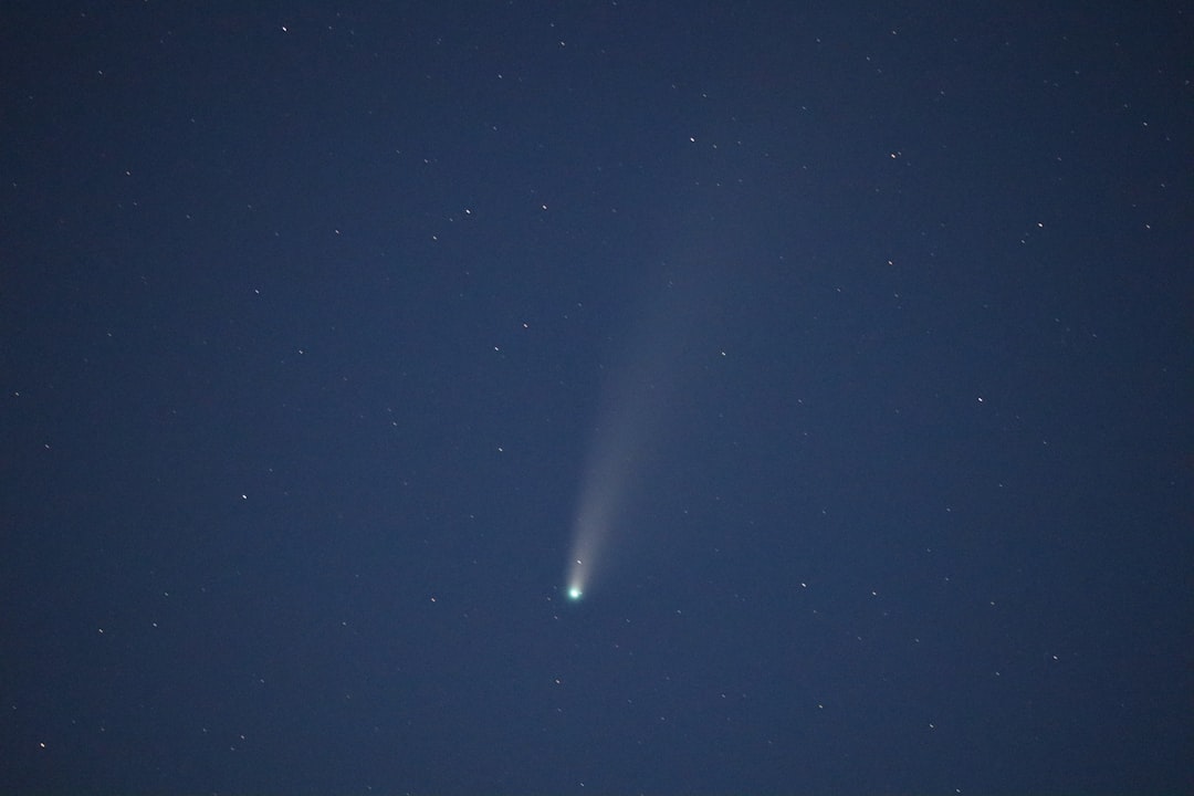 Cometa com cauda brilhante sendo observado através de telescópio no céu noturno