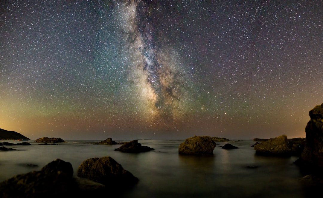 Via Lactea capturada em longa exposicao sobre paisagem escura