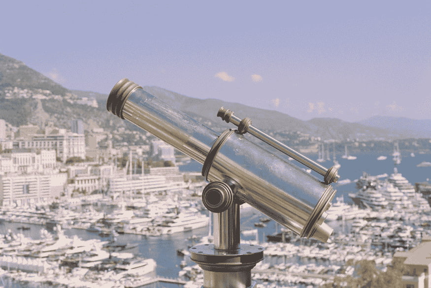Telescópio instalado em mirante com vista urbana e costeira, exemplo de equipamento usado por iniciantes na observação astronômica.