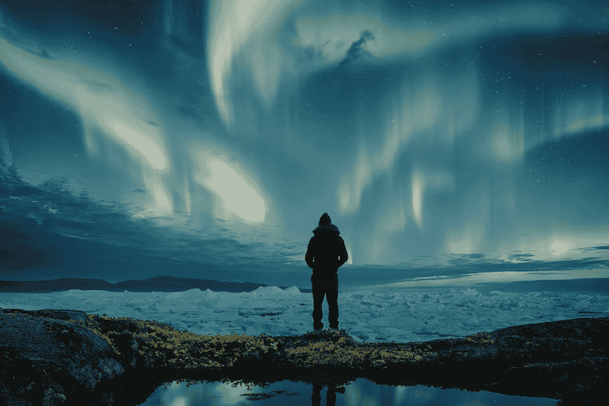 Pessoa observando aurora no céu noturno, experiência comum em eventos de observação em regiões com fenômenos atmosféricos.