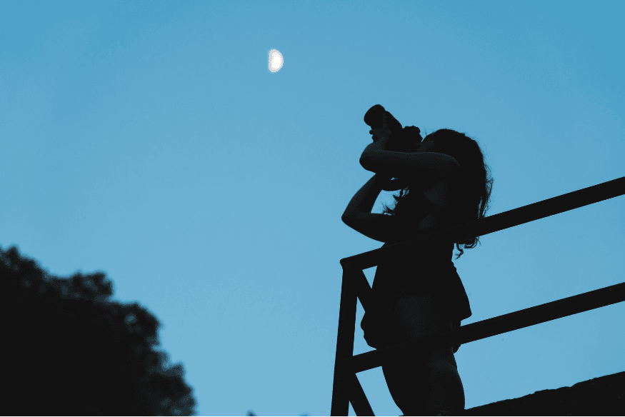 Pessoa fotografando a Lua crescente ao anoitecer, mostrando uma situação comum para registrar a Lua em diferentes fases.