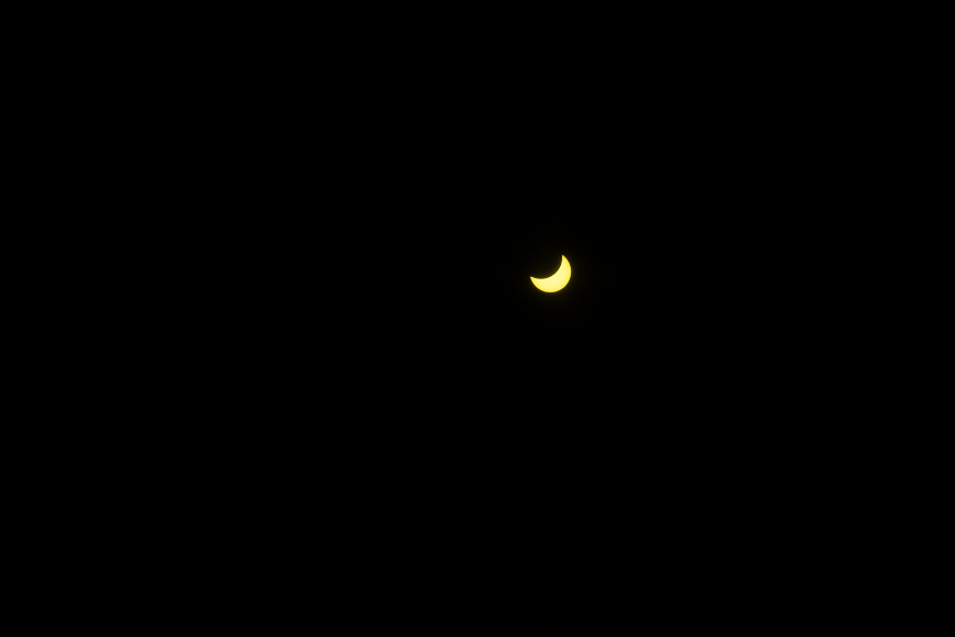 Eclipse lunar parcial com pequena parte iluminada visível no céu totalmente escuro, destacando o início do fenômeno.