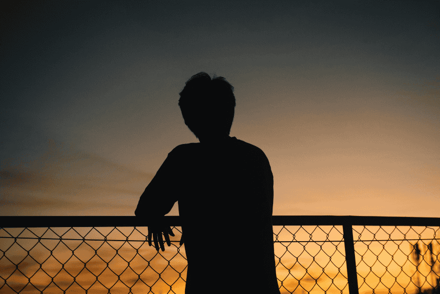 Silhueta de pessoa observando o céu ao entardecer, momento em que satélites ficam mais visíveis logo após o pôr do sol.