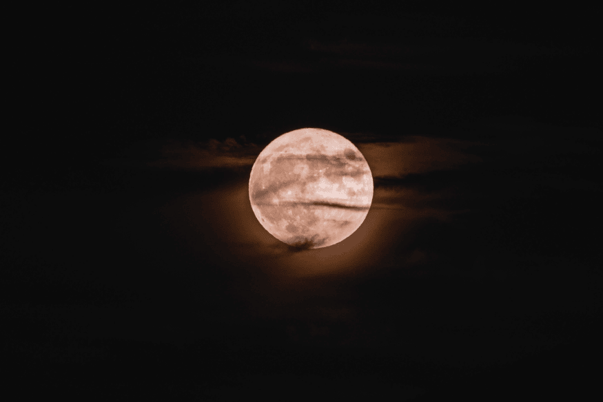 Superlua cheia com nuvens finas passando à frente, criando um efeito suave no céu noturno.