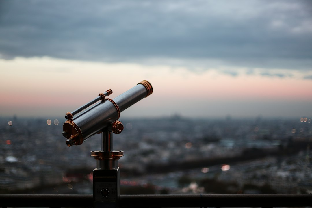 Pessoa observando o ceu noturno com telescopio refrator em area aberta
