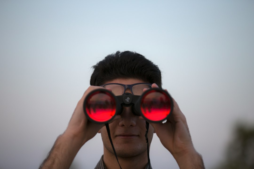 Pessoa usando binoculos para observar o ceu estrelado a noite
