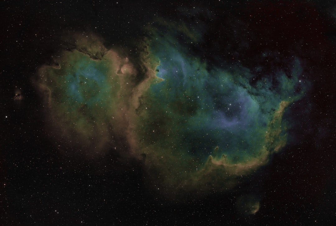 Nebulosa colorida com regioes de formacao estelar em tons de vermelho e azul