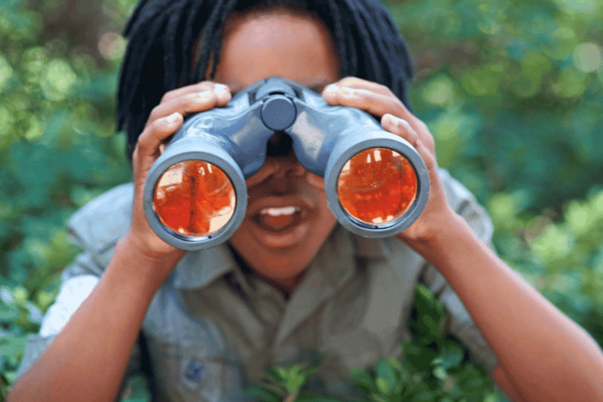 Criança observando aves com binóculo durante trilha no Pantanal