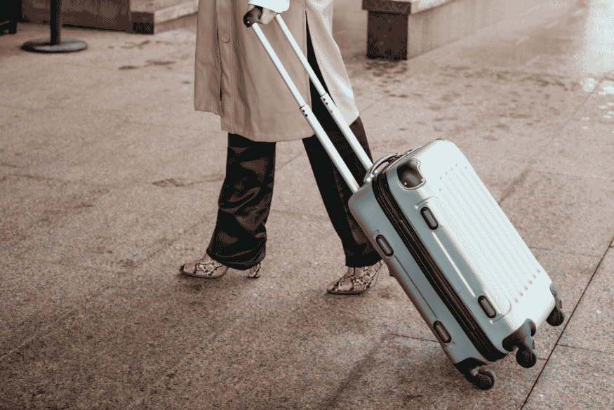 Pessoa puxando uma mala de mão em terminal de aeroporto