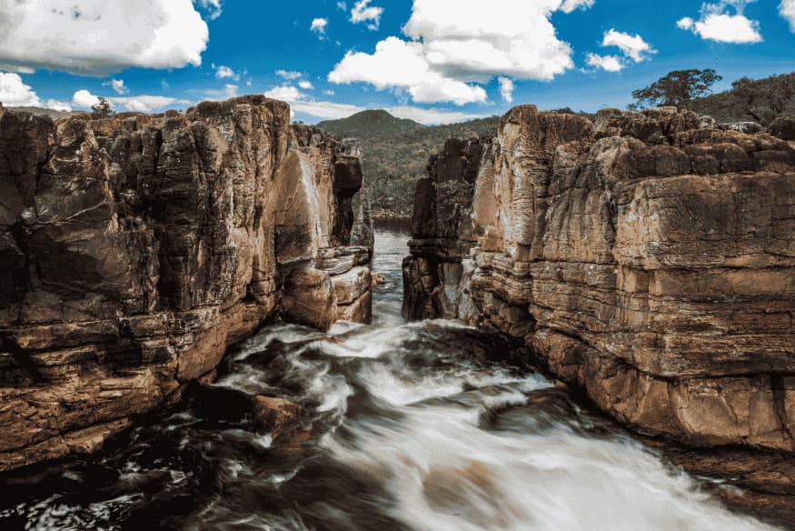 Rio passando por cânion rochoso na Chapada dos Veadeiros com céu azul