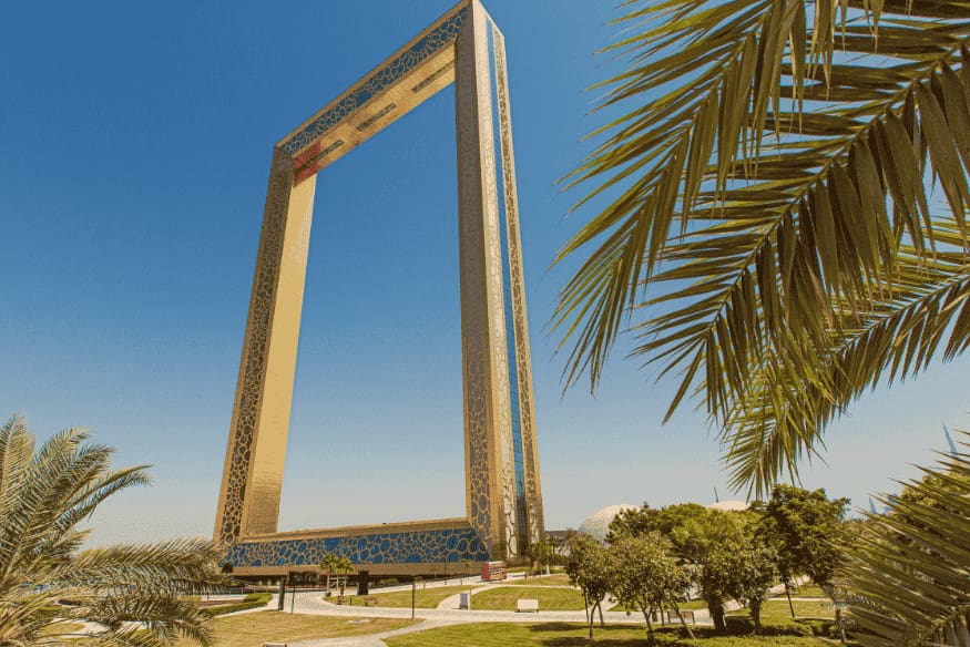 Estrutura moderna da Dubai Frame em um parque, cercada por palmeiras