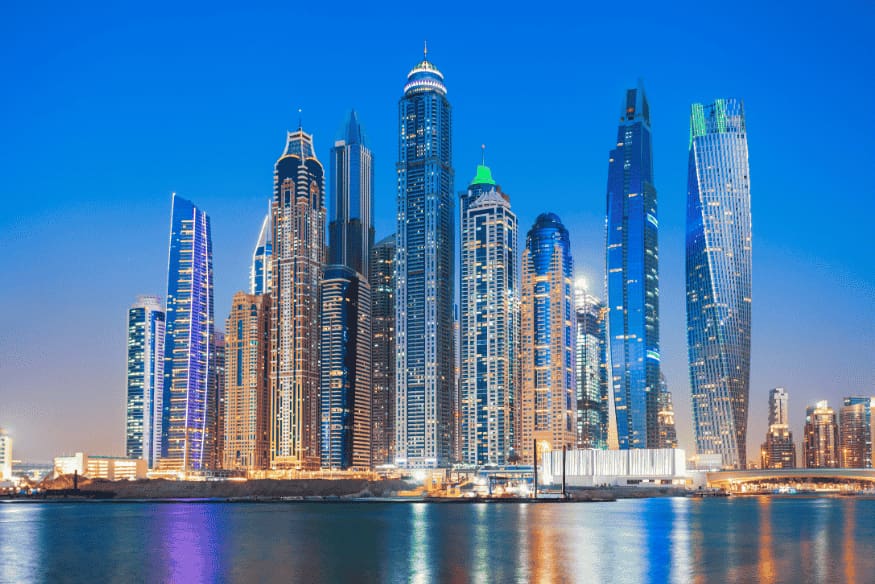 Skyline noturno de Dubai com arranha-céus iluminados refletindo no mar