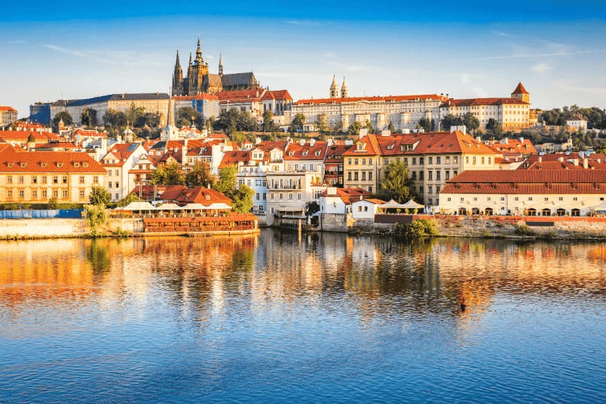 Vista panorâmica de Praga com o Castelo e casas históricas às margens do rio Moldava