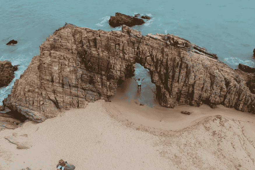 Pedra Furada em Jericoacoara com turista em pé no arco rochoso
