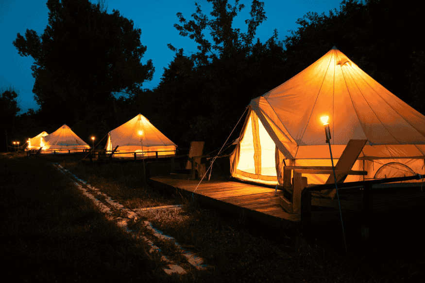 Barracas de glamping iluminadas à noite em meio a árvores