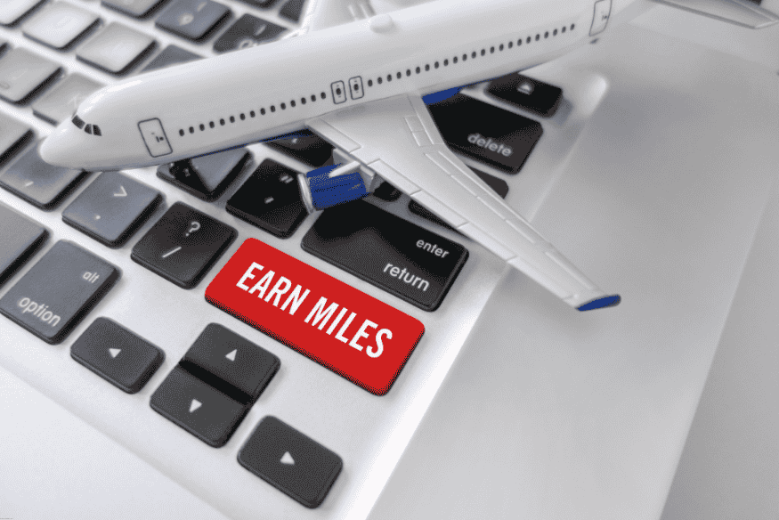 Teclado com botão vermelho “Earn Miles” e avião de brinquedo sobre as teclas