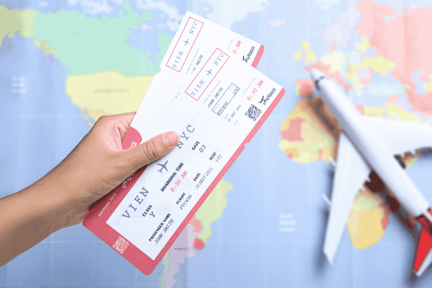 Pessoa segurando passagens aéreas com um mapa-múndi ao fundo