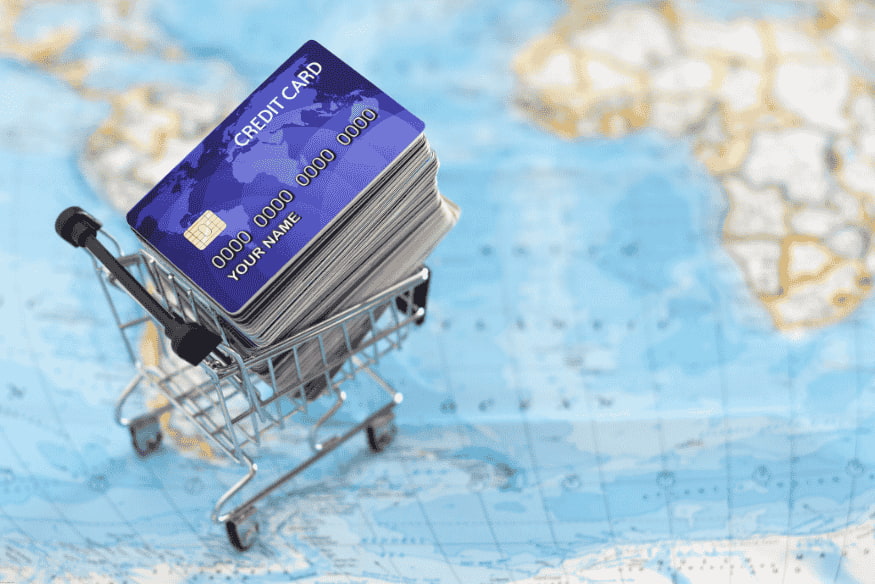 Cartões de crédito empilhados em um carrinho de compras sobre um mapa-múndi