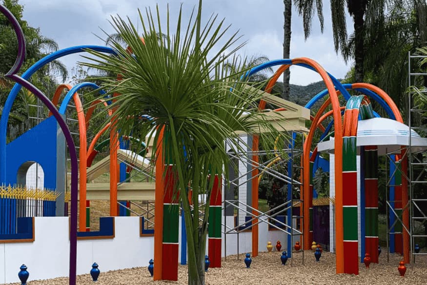 Instalação colorida no Instituto Inhotim, com arcos e estruturas artísticas em meio à vegetação tropical