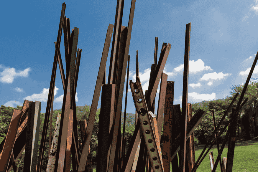 Escultura feita com vigas de ferro enferrujadas posicionadas verticalmente no gramado de Inhotim