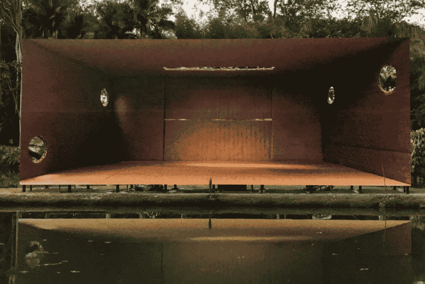 Galeria de arte moderna em formato retangular, com estrutura metálica avermelhada e aberturas circulares