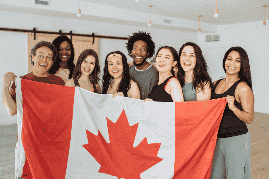 Grupo diverso de pessoas segurando uma bandeira canadense