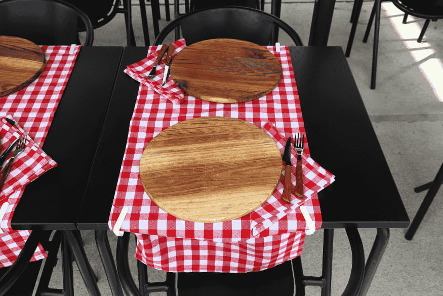 Mesa de restaurante típico em Lisboa com toalha xadrez vermelha e pratos de madeira