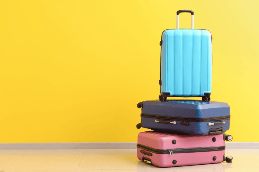 Três malas coloridas empilhadas sobre fundo amarelo simbolizando organização de bagagem
