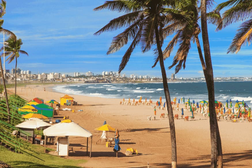 Praia urbana com barracas, coqueiros e guarda-sóis coloridos em Salvador, Bahia