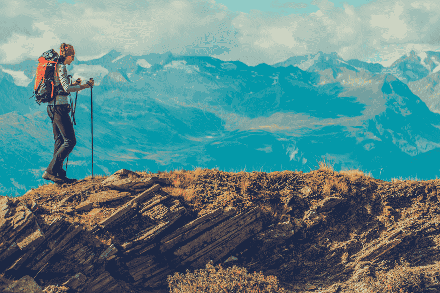 Mochileiro caminhando em trilha de montanha com bastões