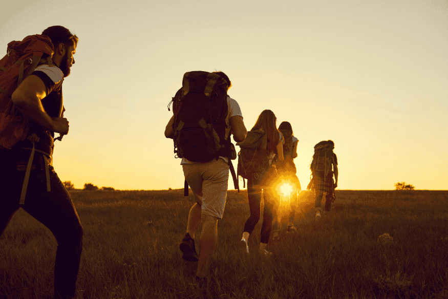 Grupo de mochileiros caminhando ao pôr do sol
