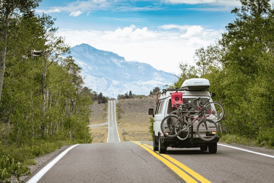 Van com bicicletas na estrada em meio à paisagem montanhosa do norte da Argentina.