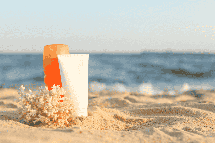 Protetores solares sobre a areia em praia com corais
