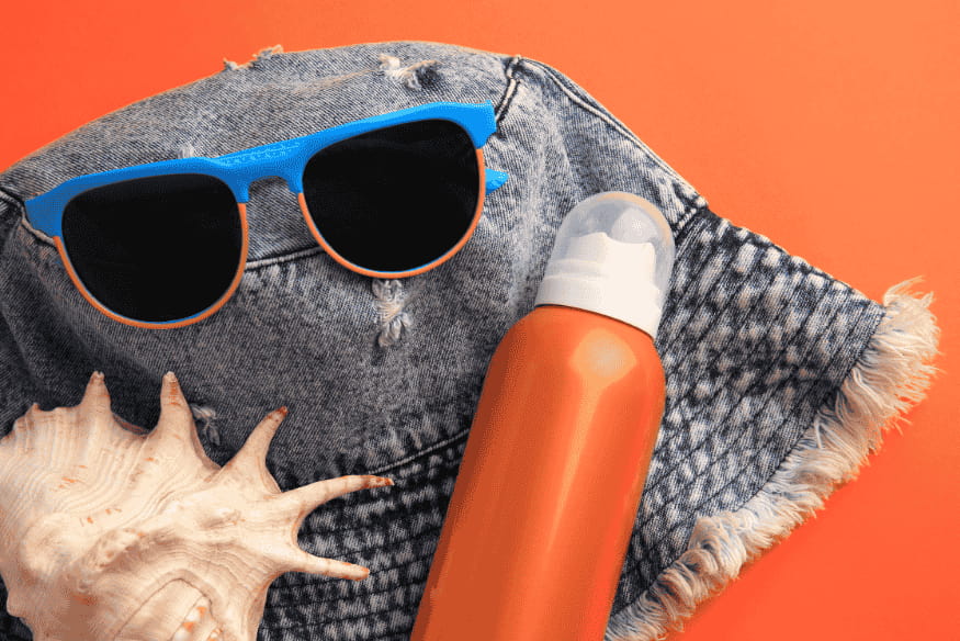 Acessórios de praia e protetor solar reef safe sobre fundo laranja