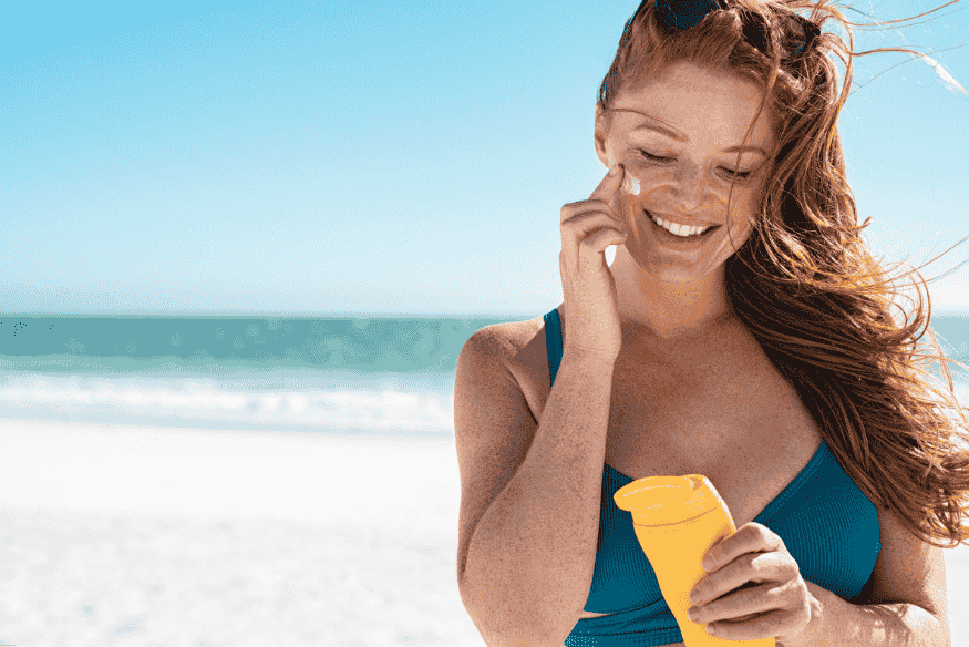 Mulher aplicando protetor solar biodegradável em praia ensolarada
