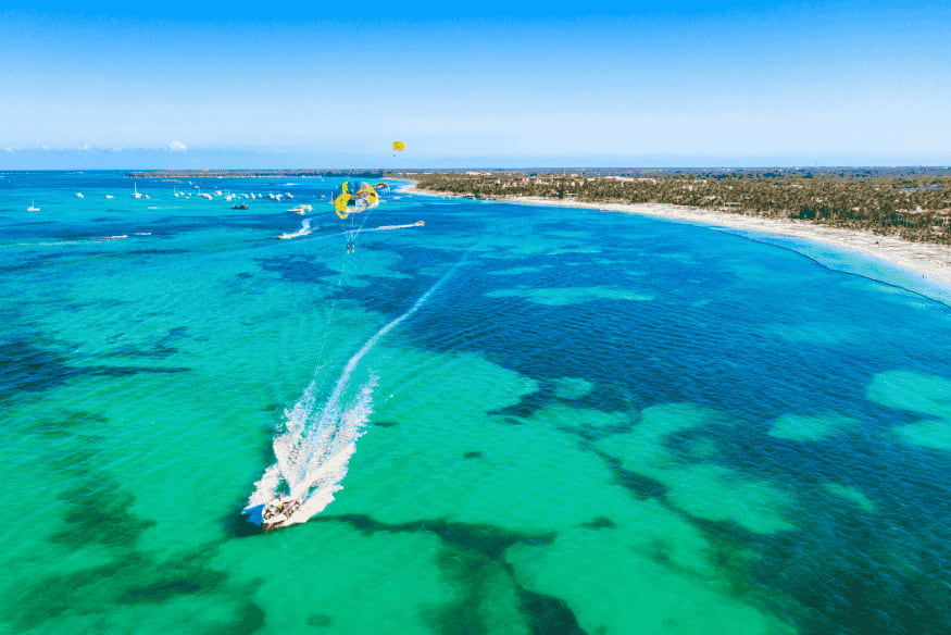 Pessoa praticando parasailing em Punta Cana com vista aérea do mar caribenho
