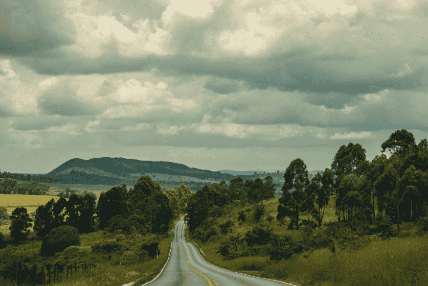 Trecho da Estrada Real cercado por vegetação e montanhas de Minas Gerais