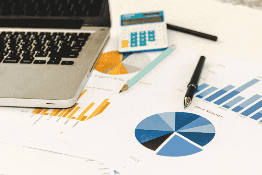 Gráficos financeiros ao lado de notebook e calculadora.