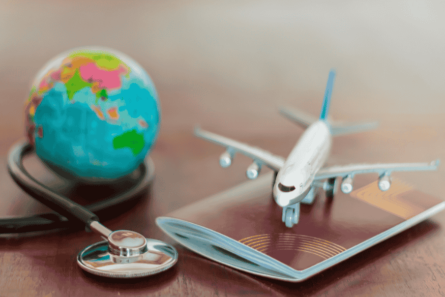 Estetoscópio ao redor de um globo, com avião sobre passaporte