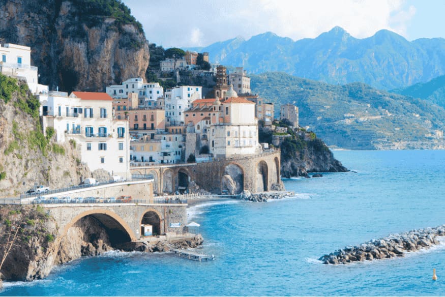 Vila costeira com casas coloridas sobre arcos de pedra à beira-mar na Costa Amalfitana, uma das cidades mais encantadoras do roteiro.