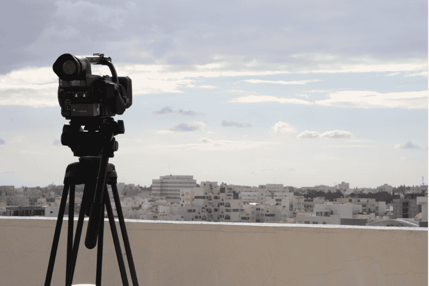 Câmera em tripé durante o dia em ambiente urbano, exemplo de treino de astrofotografia e preparação para longas exposições noturnas.