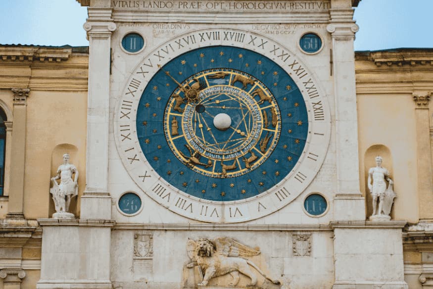 Relógio astronômico monumental em edifício histórico com mostrador azul e referências aos corpos celestes