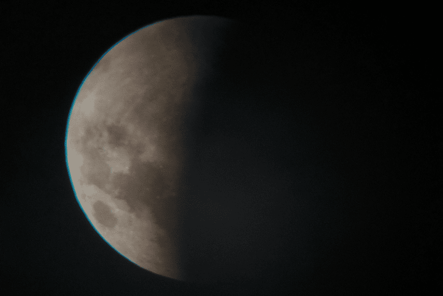 Lua com parte iluminada e parte na sombra da Terra, mostrando fase parcial de um eclipse lunar.