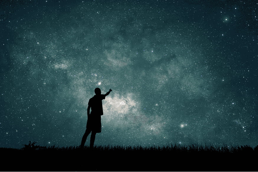 Pessoa apontando para o céu estrelado, cena que lembra a busca por exoplanetas e a possível confusão entre estrelas e planetas distantes.