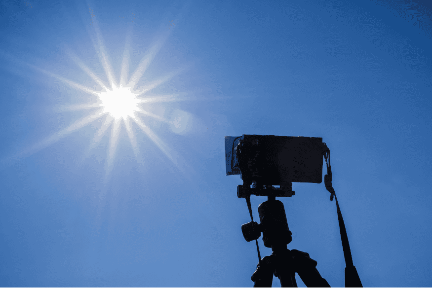 Câmera apontada para o Sol em céu limpo, situação que exige filtro solar apropriado para fotografar eclipses com segurança.