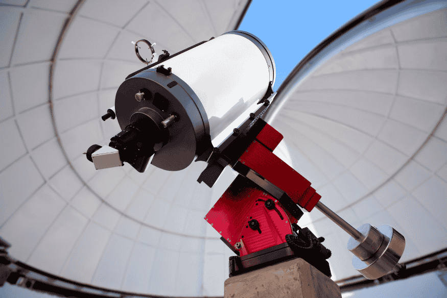 Telescópio refletor montado dentro de cúpula de observatório astronômico, exemplo de instrumento usado para diferentes tipos de observação.