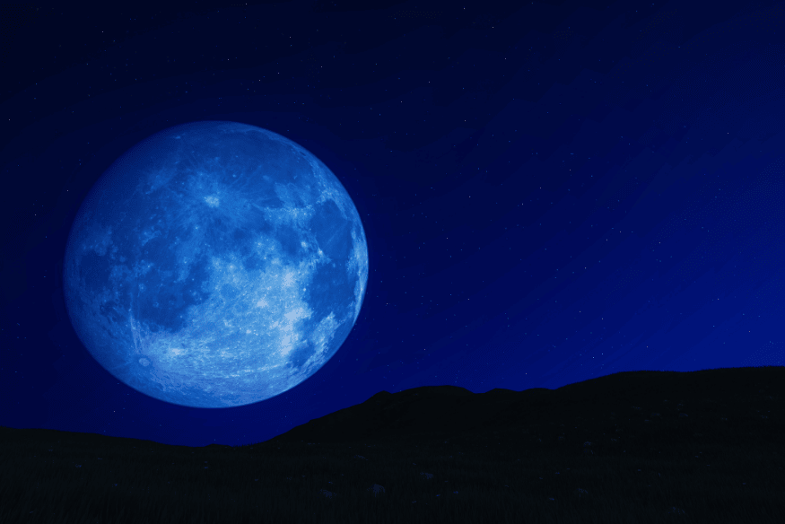 Lua azul em céu estrelado acima de montanhas escuras, destacando o brilho da Lua cheia.