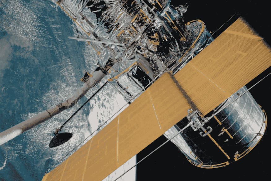 Telescópio espacial em órbita da Terra com painéis solares abertos, exemplo de instrumento usado para observar o Universo fora da atmosfera.